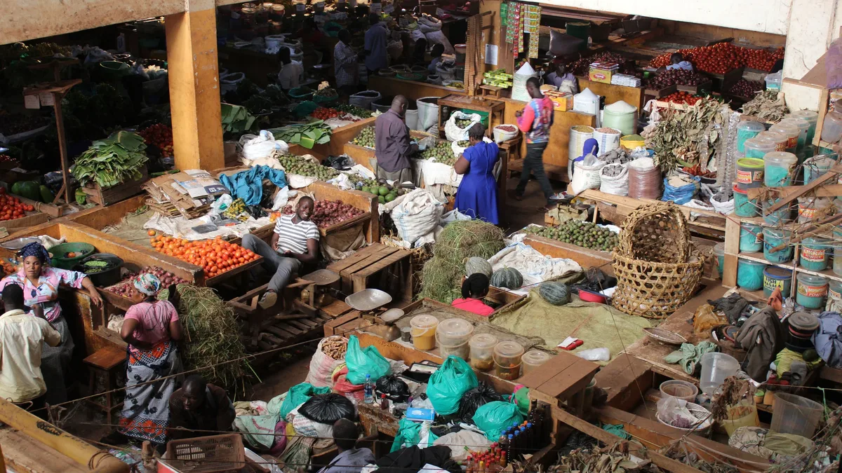 A bustling marketplace with numerous vendors and customers, showcasing a variety of goods and produce.