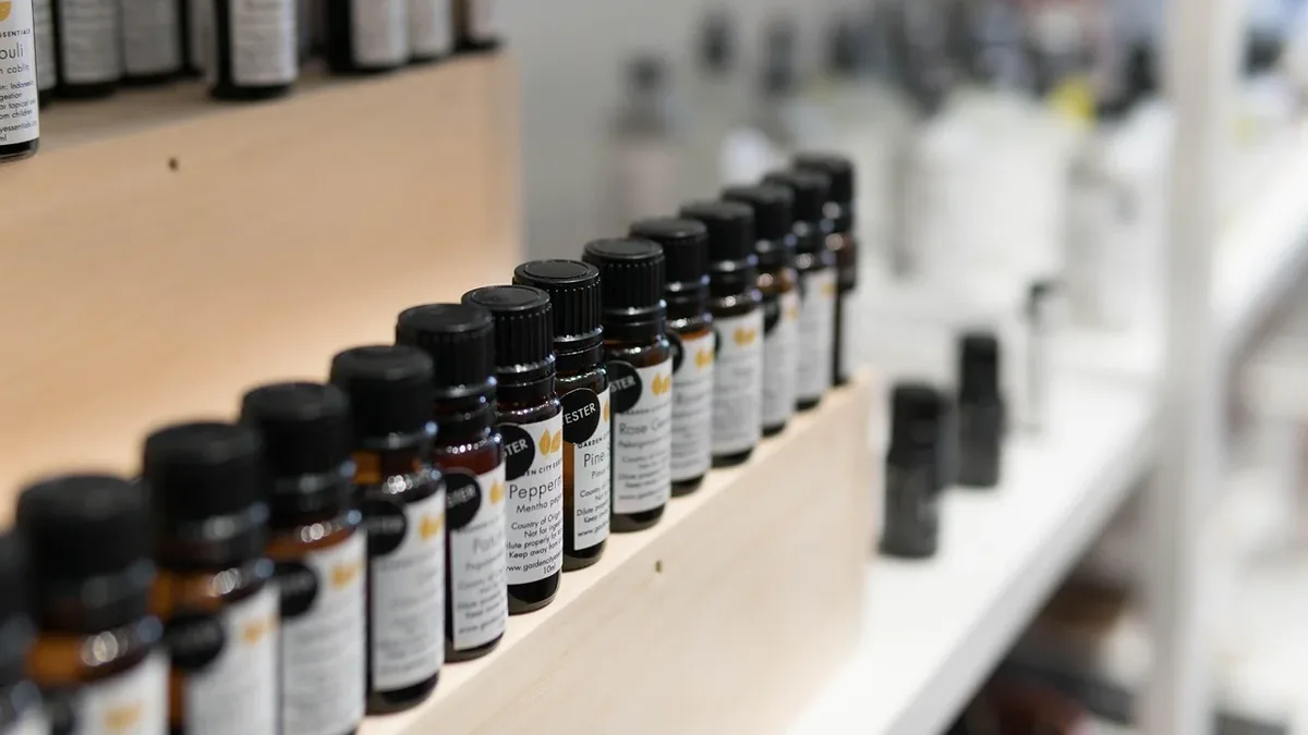 A row of small glass bottles with black caps and white labels on a shelf in a store.